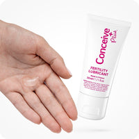 Conceive Plus Men's Fertility Support + Lubricant showing a 30ml fertility lubricant tube beside an open palm with a visible amount of clear gel, photographed against a white background to highlight texture, application method, and ease of use for male reproductive health.