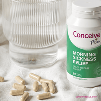 Conceive Plus morning sickness relief supplement bottle with capsules and a glass of water on a light background